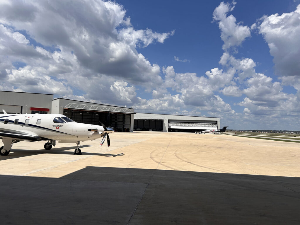 private plane with three airplane hangers in the background