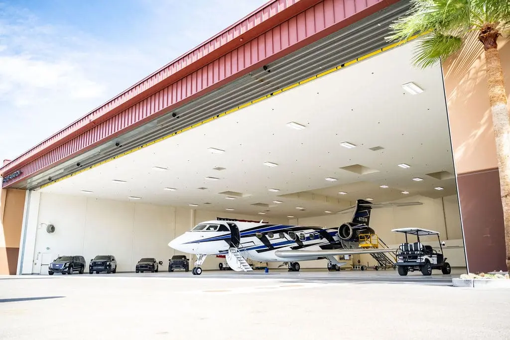 private plane in a hanger at Quail Air Center with a golf cart nearby and several black SUVs in the background