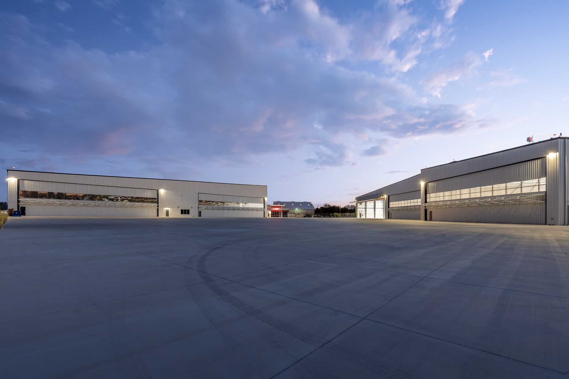 view of two buildings housing airplane hangers in San Antonio at dusk